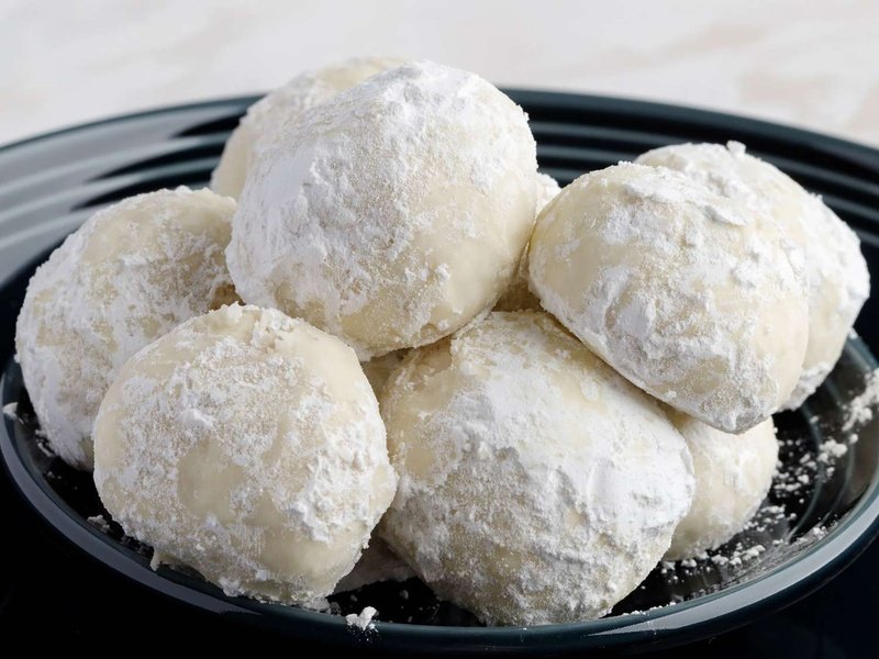 a low angle close up view of a pile of Russian tea cakes perfectly dusted with confectioner's sugar