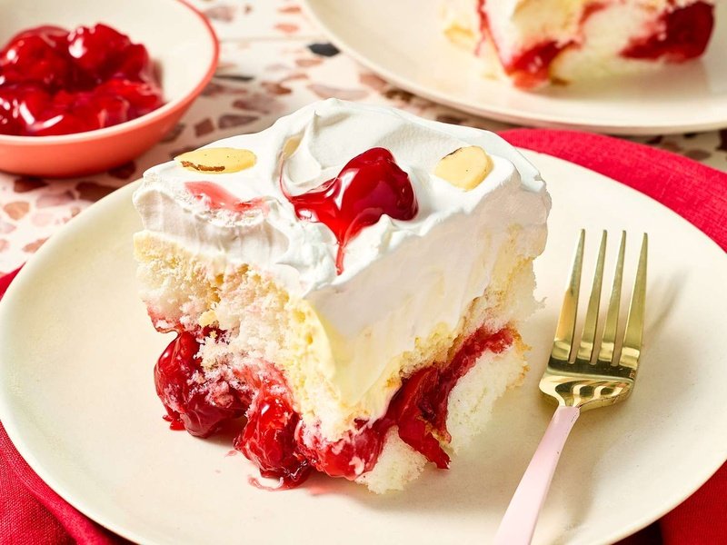 Slice of layered dessert with whipped topping and cherry garnish