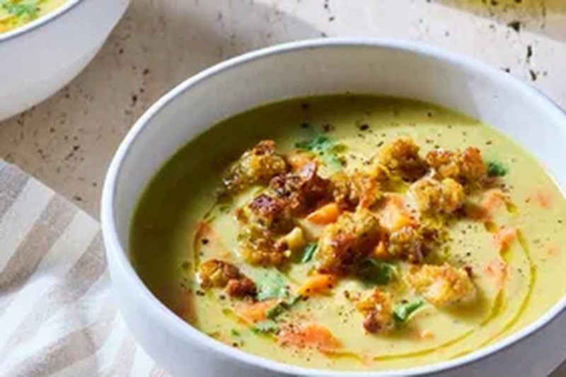 A bowl of curried soup topped with croutons on a table