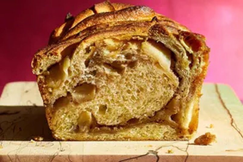 A chaispiced apple babka loaf on a cutting board cut to reveal the interior swirls and apple pieces