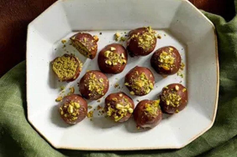 A plate of chocolate truffles topped with chopped nuts arranged neatly on a white platter