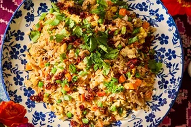 A plate of fried rice garnished with herbs and vegetables