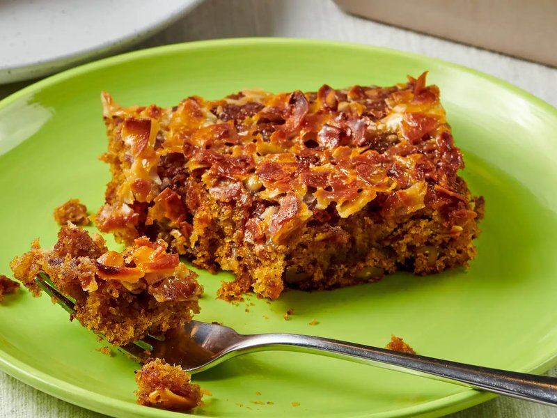 A slice of cake on a green plate with a fork beside it
