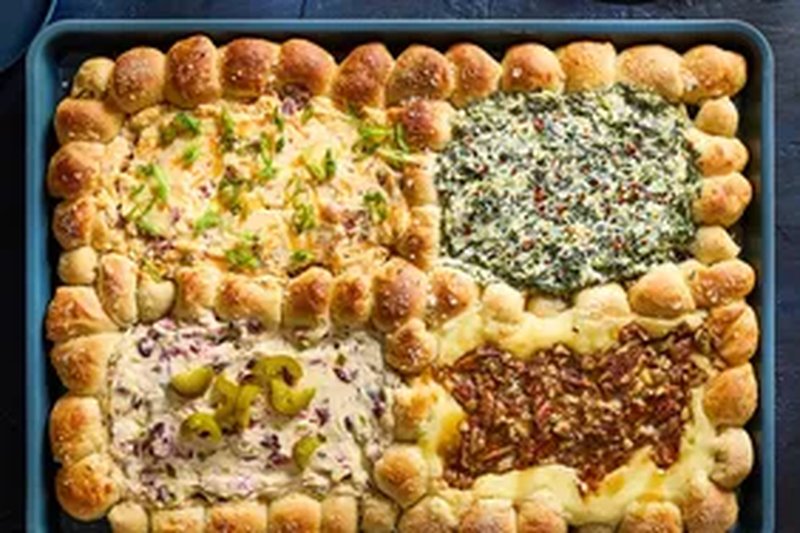 A tray of four different dips surrounded by dough balls