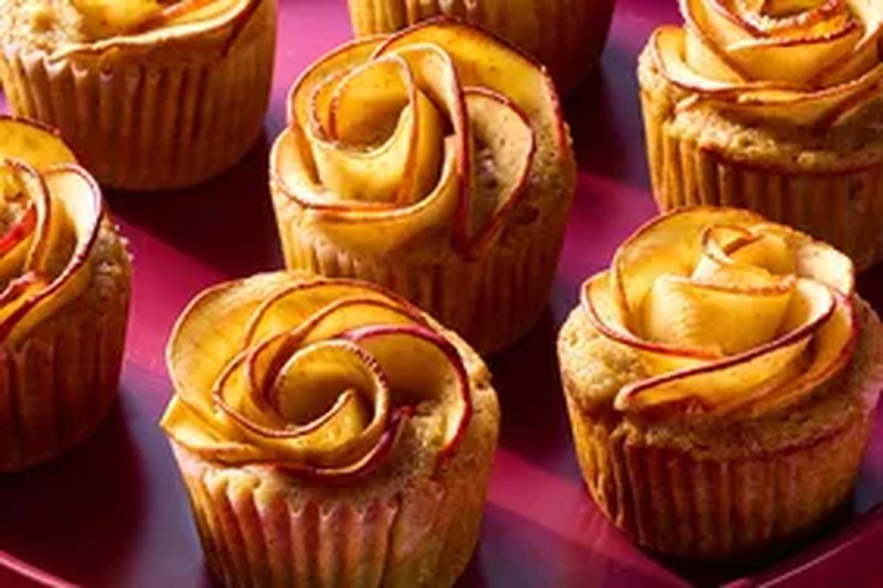 Apple rose muffins displayed on a red surface