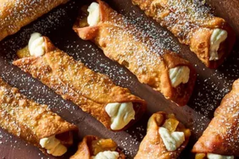 Cannoli filled with cream and apple pieces displayed on a surface