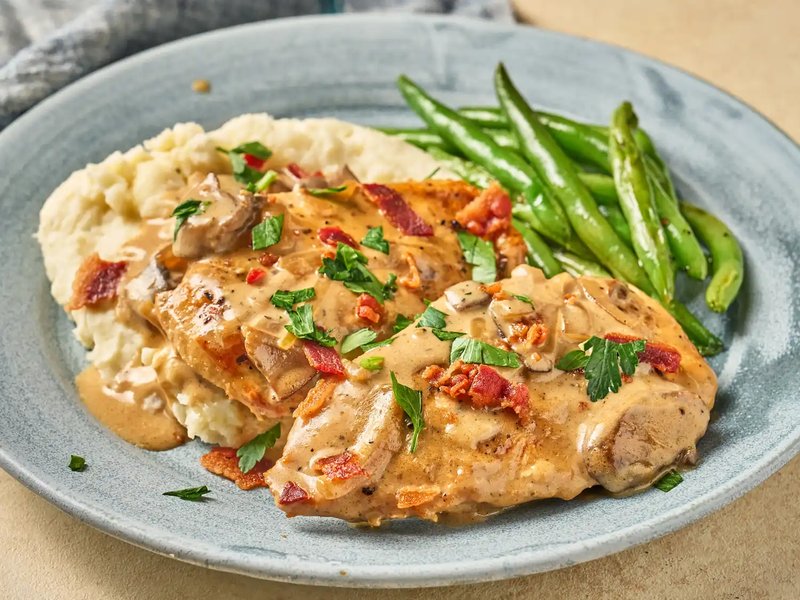 Chicken smothered in creamy sauce with mashed potatoes and green beans
