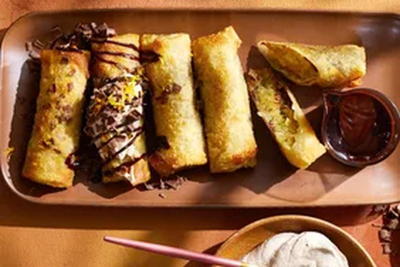 Chocolate and apple egg rolls arranged on a plate with sauces and garnishes