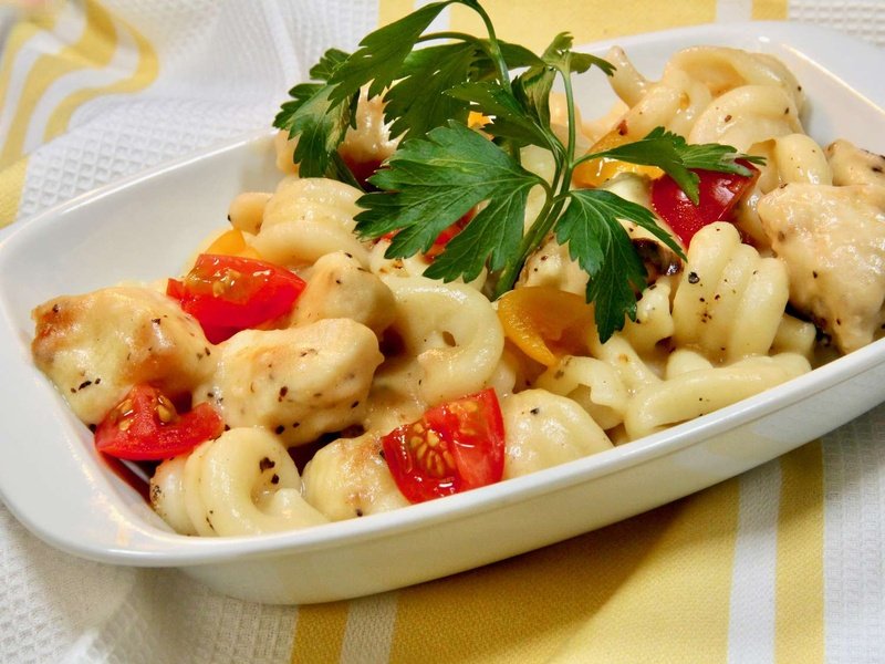 Pasta with chicken, tomato and lemon sauce in white baking dish garnished with parsley