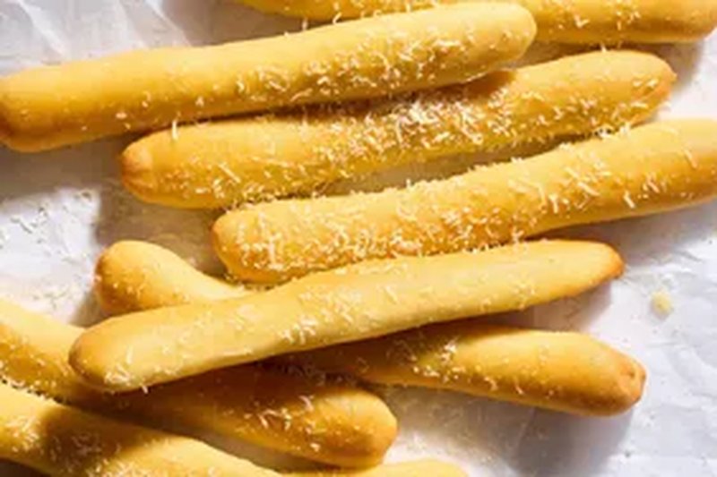 Several breadsticks garnished with grated cheese placed on a surface