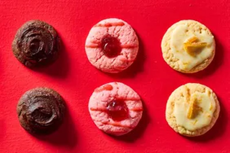 Six cookies with various toppings arranged in two rows on a red background