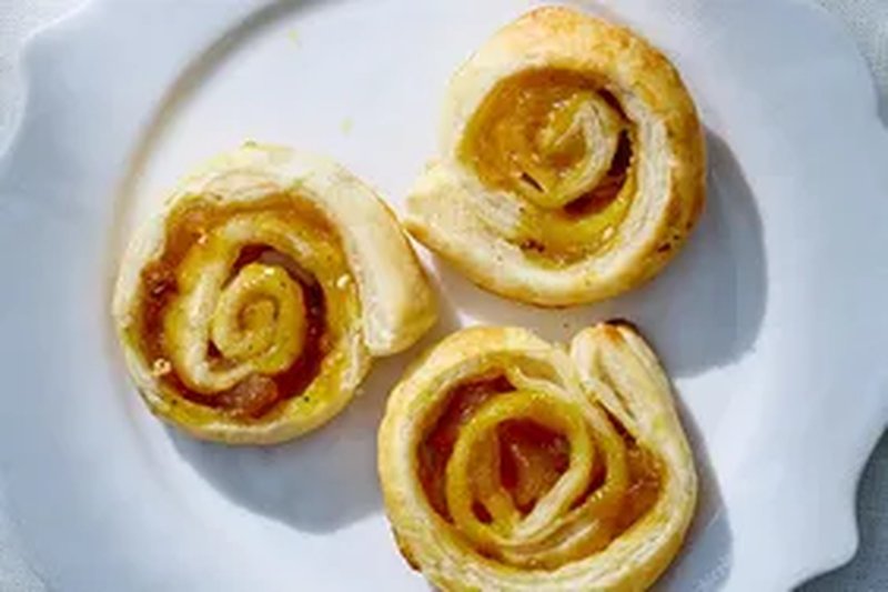 Three curry chutney pinwheels on a white plate showcasing a swirled pastry filled with chutney