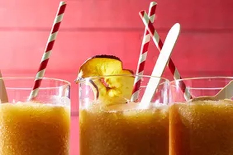 Three glasses of apple slush with straws and garnished with apple slices