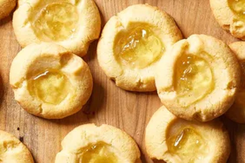Thumbprint cookies filled with apple jelly displayed on a wooden surface