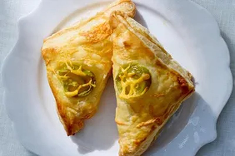Two pastry turnovers topped with jalapeo slices on a white plate