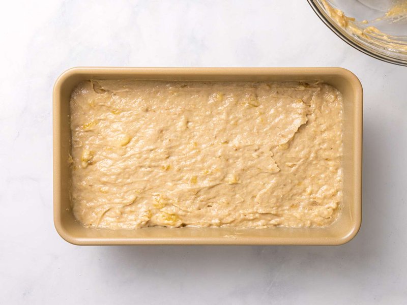 Batter spread evenly in a rectangular baking pan ready to be baked into banana bread