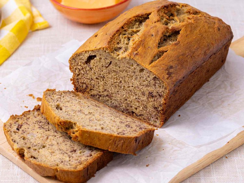 Loaf of banana bread with slices cut resting on parchment paper